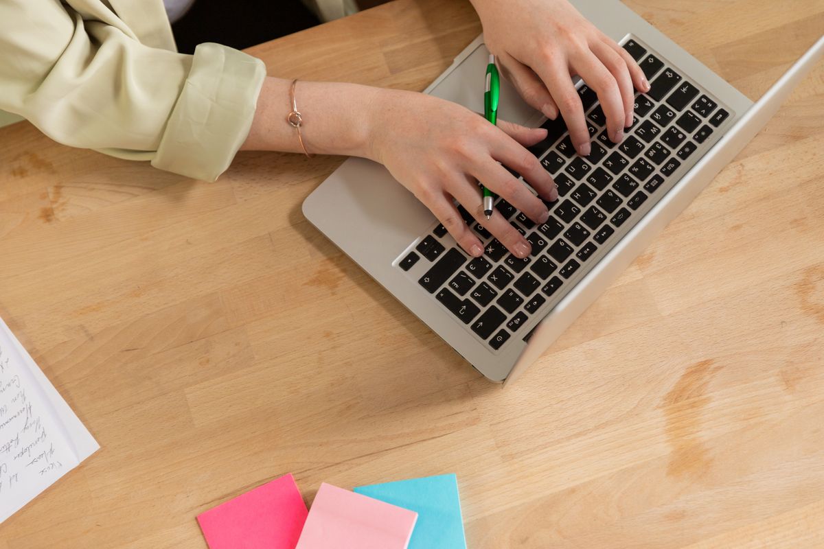 Editing and cleaning up a transcript on a laptop with notes