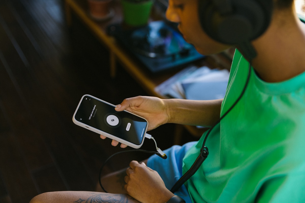 Person with headphones listening to their iPhone reading aloud at home